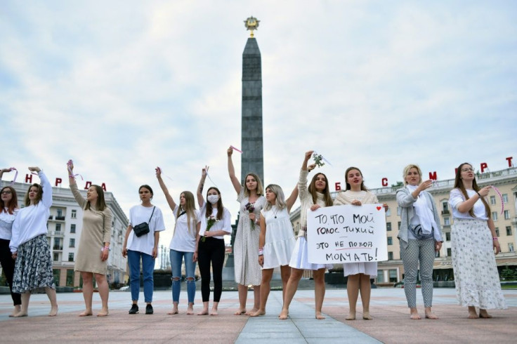 Women join hands to form a human chain, many wearing white and holding flowers, in the capital Minsk