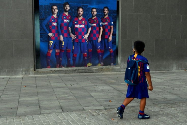 A boy wearing a Barcelona kit looks at a poster depicting players including Lionel Messi