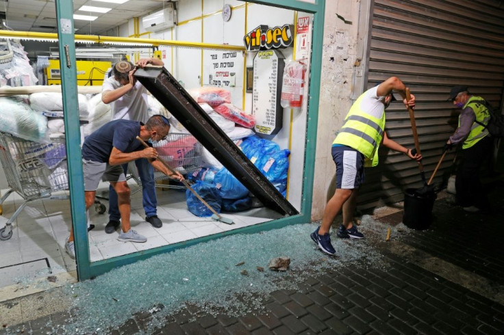 Israeli men remove the shattered glass window of a laundry shop in the southern coastal town of Ashdod following a rocket attack from the Gaza Strip