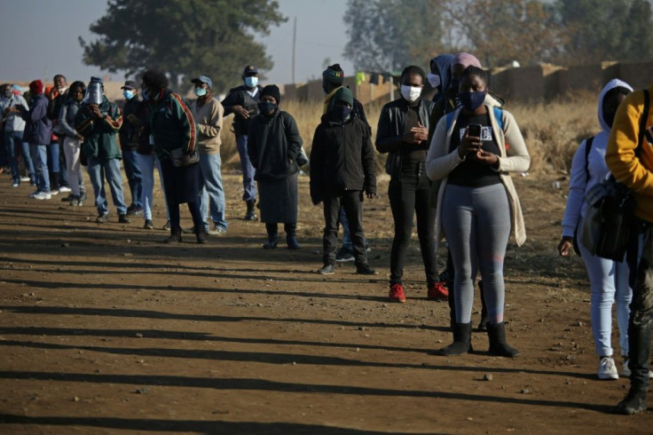 Commuters in South Africa wearing face masks wait outside the Pienaarspoort Station, East of Pretoria to board a train