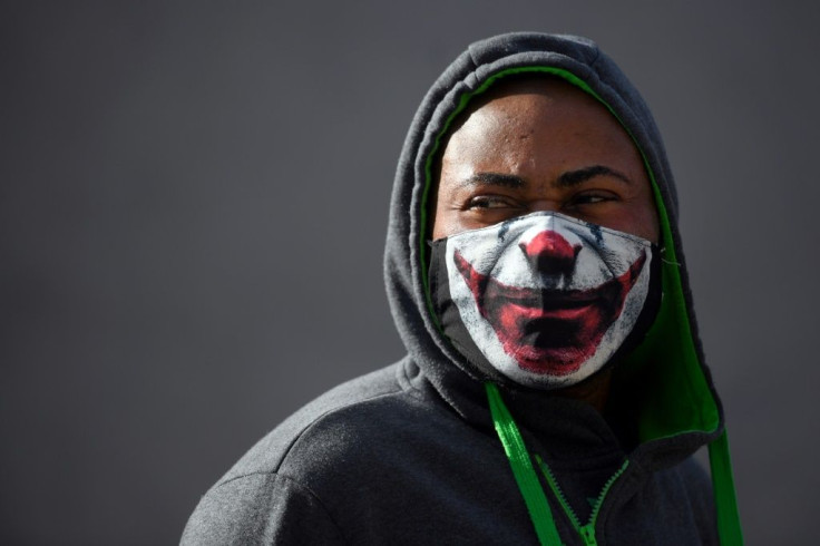 A man wears a facemask depicting the mouth of the Batman villain "The Joker"