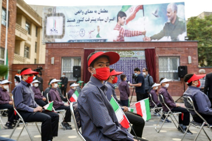 Mask-clad schoolchildren sit in Tehran in September 2020 before a billboard featuring the image of late general Qasem Soleimani