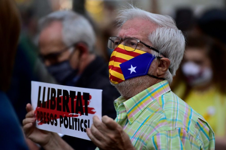 A man wearing a face mask bearing the Catalan pro-independence flag holds a placard reading "Free political prisoners"