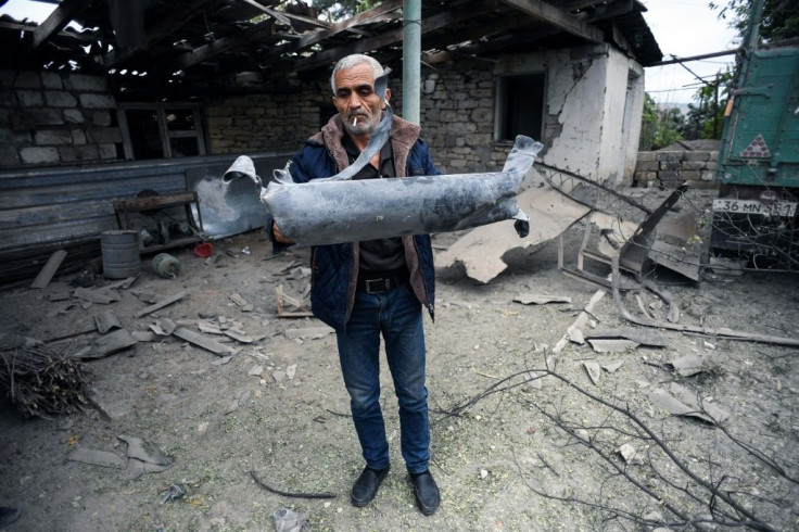 A man shows a shell fragment in the yard of a house damaged by shelling during fighting between Armenia and Azerbaijan over the breakaway Nagorny Karabakh region