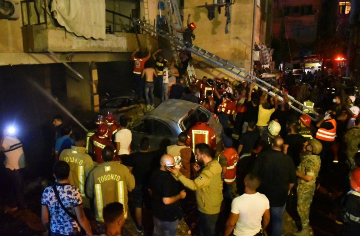 Members of Lebanese Civil Defence and firefighters evacuate people from their apartments after a fuel tank exploded in Beirut's Tariq al-Jdide neighbourhood