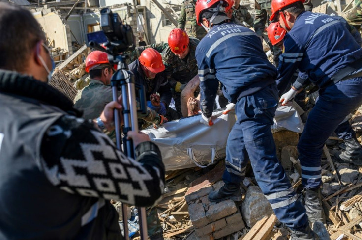 Rescuers carry away the body of a victim where a rocket struck in the Azerbaijani city of Ganja on October 11