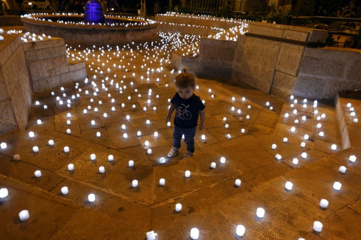 A child walks amid candles placed by Israeli anti-government activists to honour victims of the coronavirus pandemic in Jerusalem