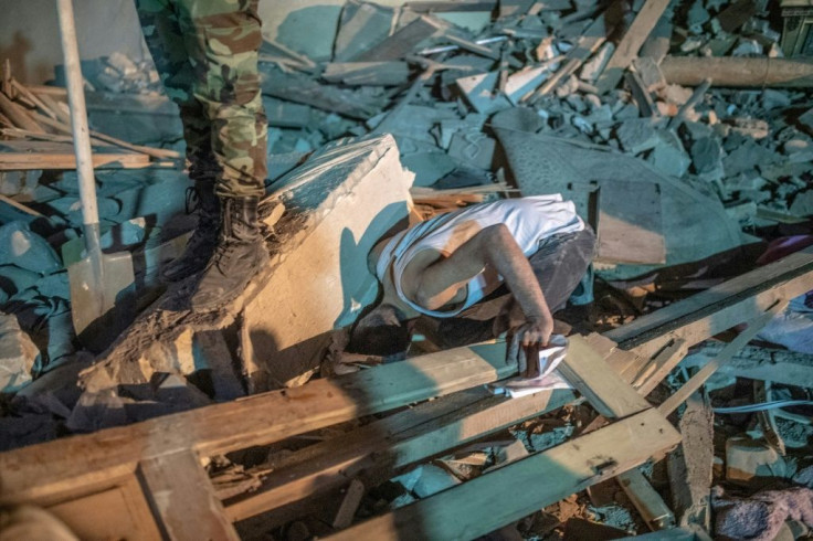 A resident searches for relatives in the rubble as rescue teams work at a site hit by a rocket during the fighting over the breakaway region of Nagorno-Karabakh, in the city of Ganja, Azerbaijan early on October 17, 2020