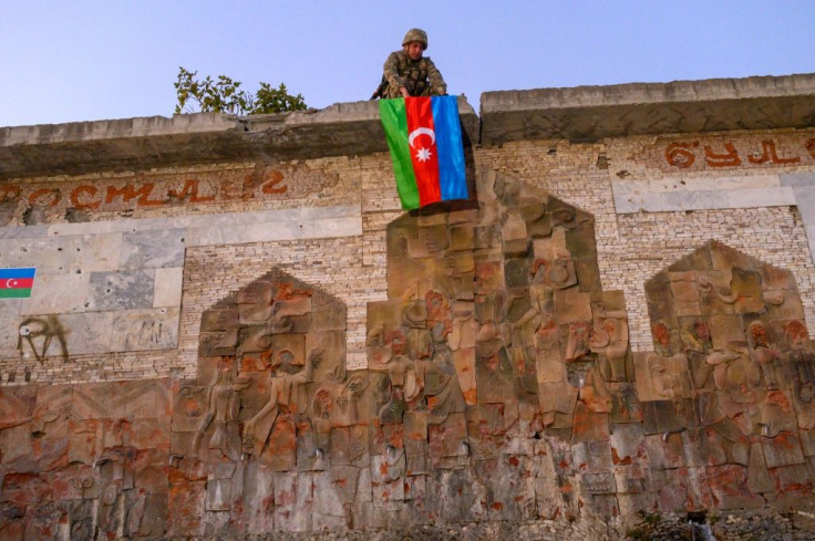 An Azeri soldier hangs the flag of Azerbaijan on a wall in Jabrayil