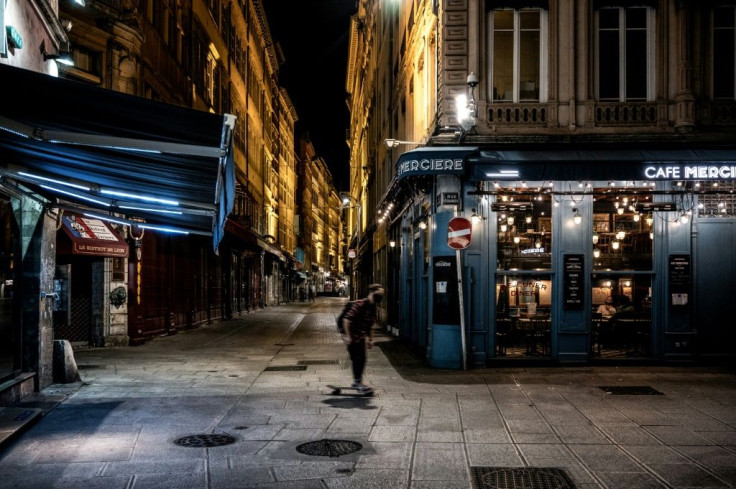 A man rides his skateboard past the deserted Lyon rue Merciere during the first night of curfew