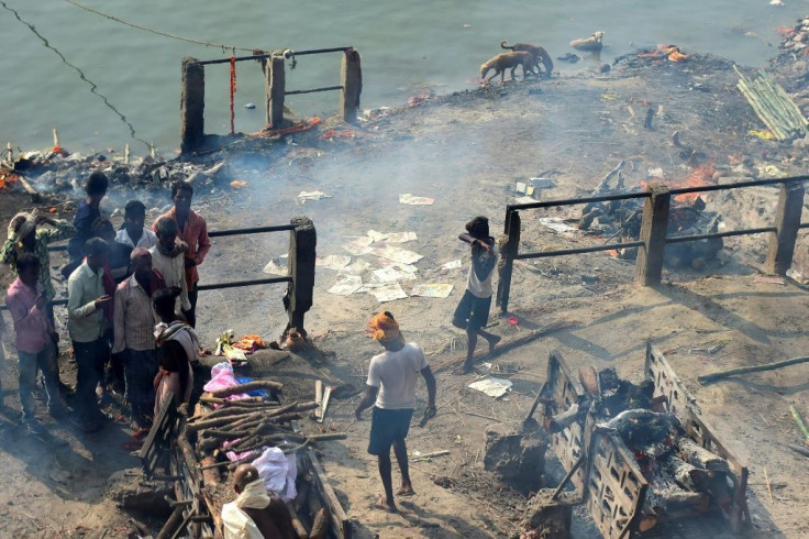 A young boy (R) looks for discarded clothes used to wrap dead bodies for final rites for money, at a cremation site in Varanasi, India