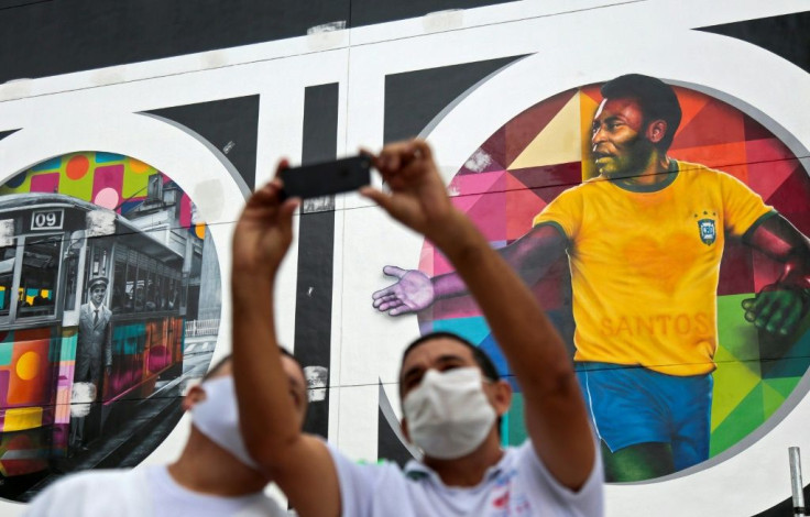 Fans pose for selfies next to a mural in Santos, Sao Paulo state, Brazil by Brazilian artist Kobra depicting Pele in his heyday