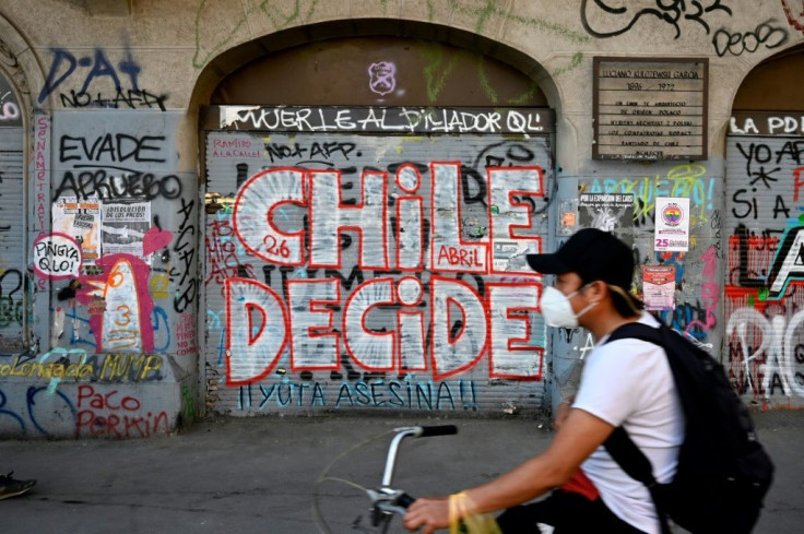 A man rides a bicycle past a wall a graffiti reading "Chile decides" in Santiago, on October 23, 2020, two days ahead of a referendum
