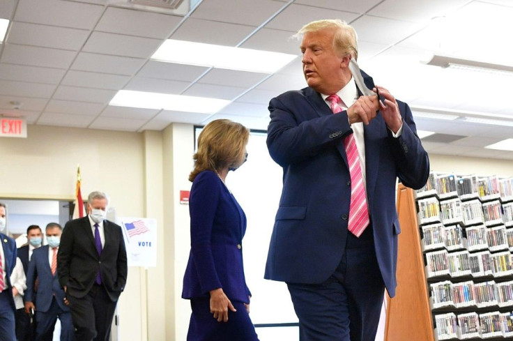 US President Donald Trump takes off his mask before speaking to the press after casting his ballot at the Palm Beach County Public Library, during early voting for the November 3 election, in West Palm Beach, Florida, on October 24, 2020