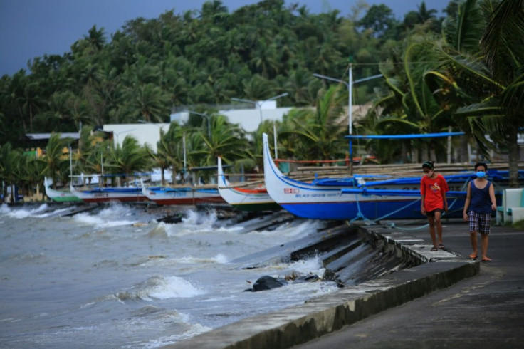 Residents walk past parked wooden boats along a boulevard in Legazpi