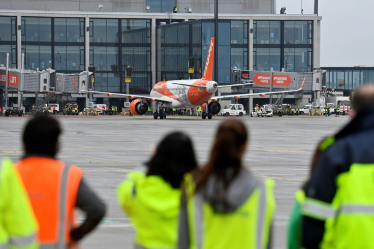 Airport workers look on as the Easyjet plane, one of the first two flights to arrive, taxis to a stop in front of the main terminal