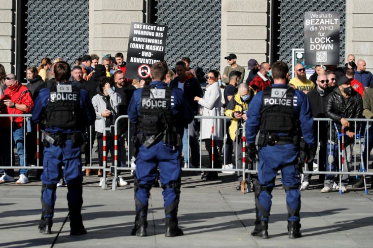 Police offers watch protestors as they stage a demonstration in Bern on October 31, 2020, to protest against new measures by Swiss authorities to rein in skyrocketing coronavirus cases in the country
