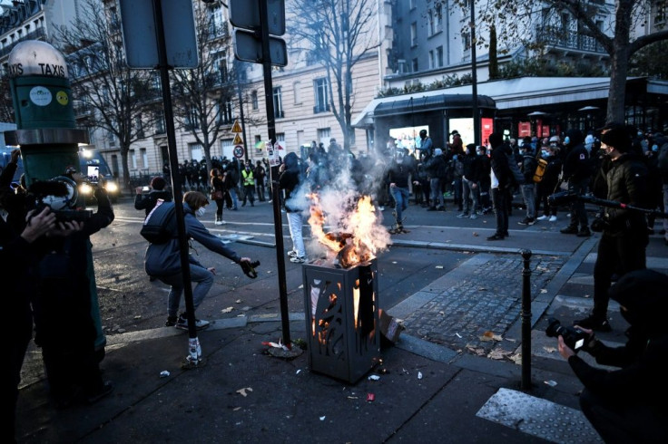 Photographers and cameramen shoot images of a burning trash bin during a demonstration in Paris against a new draft law seeking to limit the filming of police officers on duty