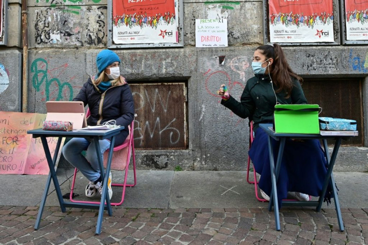 Two 12-year-olds sit in front of Italo Calvino school in Turin as they protest against school closures because of government restrictions over the Covid-19 pandemic