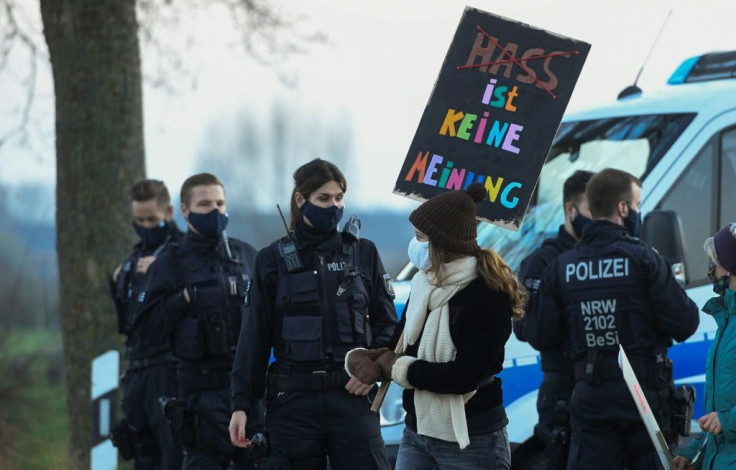 A woman with a placard reading 'hate is no opinion'  walks past police officers during an anti-AfD demonstration