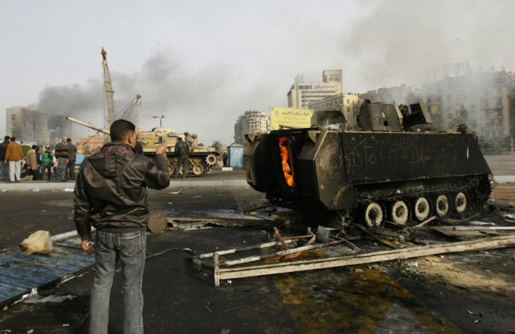 An Egyptian demonstrator uses his mobile phone to take a picture of a burnt army tank during clashes in central Cairo on January 29, 2011