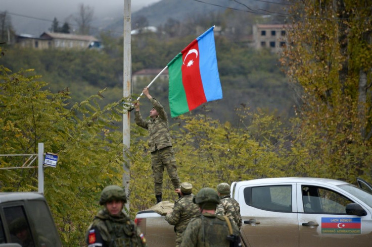 An Azerbaijani soldier fixes a national flag on a lamp post in the town of Lachin, the final district given up by Armenia in a peace deal that ended weeks of fighting over disputed Nagorno-Karabakh