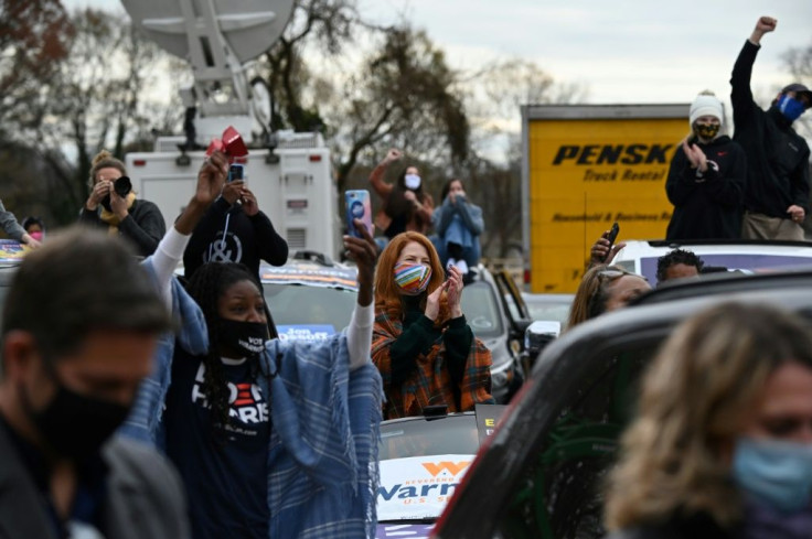 People cheer as they watch US President-elect Joe Biden address a campaign rally in Atlanta, Georgia