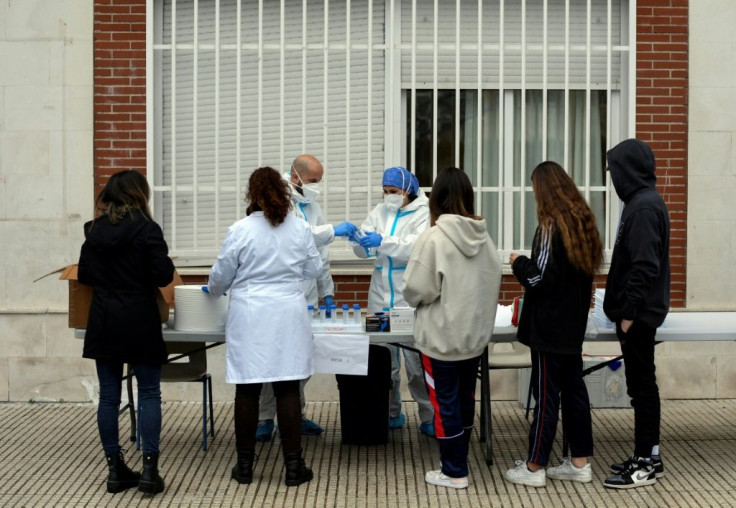 Health personnel collect saliva samples from pupils in a school in Madrid on December 17, 2020 for a study on coronavirus transmission between children and from children to adults