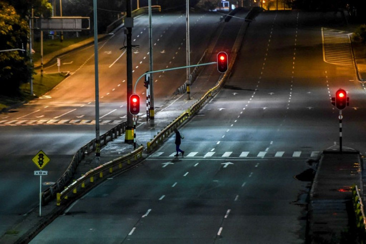 A man crosses an empty avenue in Medellin, Colombia, on January 7, 2021 as authorities placed several regions under a new lockdown after an increase in coronavirus cases