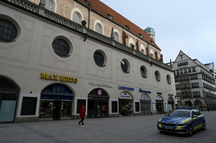 A police car is parked on a shopping street as one person walks by the closed stores, in the city centre of Munich, southern Germany, pictured on January 11, 2021, amid the ongoing novel coronavirus Covid-19 pandemic