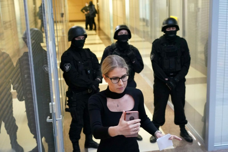 Opposition politician Lyubov Sobol uses her smartphone while standing in front of law enforcement agents in a hallway of a business centre that houses the office of opposition leader Alexei Navalny's Anti-Corruption Foundation (FBK), in Moscow in December