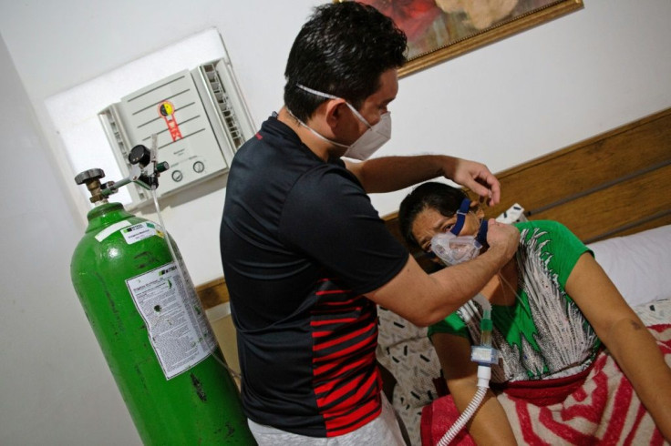 Brazilian doctor Marcos Fonseca Barbosa (L) helps his mother, who he was forced to treat at home for Covid due to a shortage of hospital beds