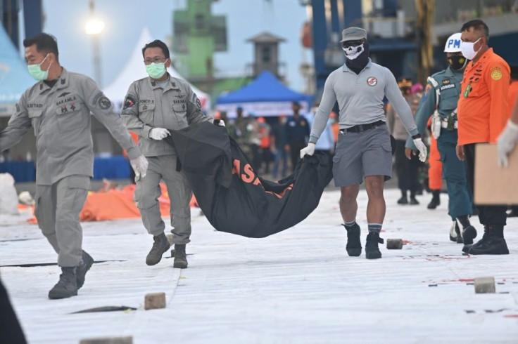 Forensic policemen carry a bag containing debris from the crashed plane