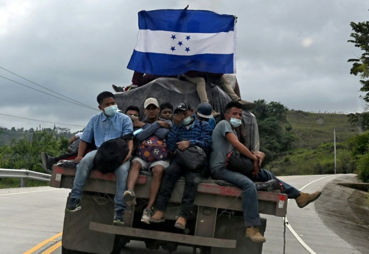 Migrants heading to the United States display an Honduran national flag as they hitchhike on the back of a truck near El Florido, in the Honduran department of Copan near the border with Guatemala
