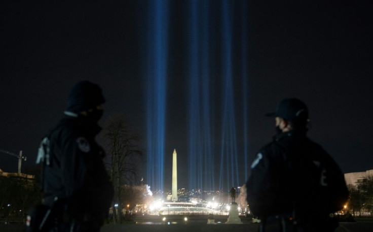 US Capitol police look on as spotlights on the National Mall frame the Washington monument during preparations for President-elect Joe Biden's inauguration