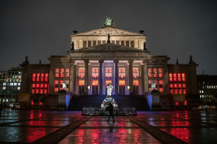 A lone pedestrian walks past the concert hall at Gendarmenmarkt illuminated in red to draw attention to the plight of cultural institutions in Berlin amid the pandemic