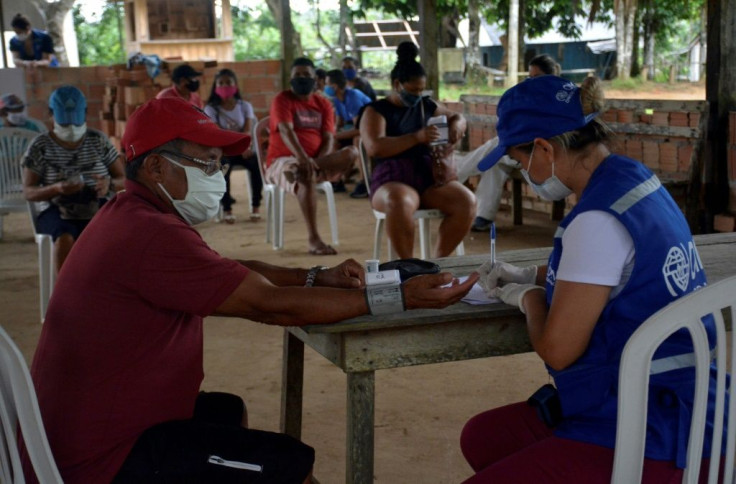 A resident with symptoms of COVID-19 receives medical assistance from a member of the International Organization for Migration (IOM) in the riverside community of Bela Vista do Jaraqui in Amazonas state, Brazil, on January 18, 2021