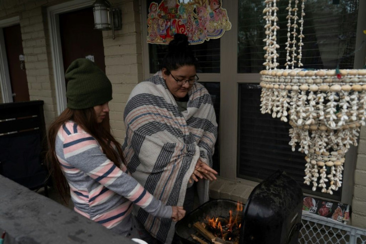 Karla Perez and Esperanza Gonzalez warm up by a barbecue grill during power outage caused by the winter storm on February 16, 2021 in Houston, Texas