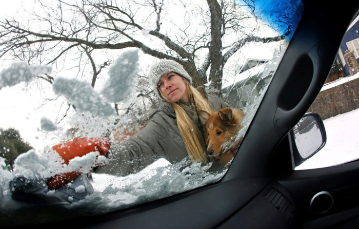 Caroline Marlett holds her dog Kit while scraping the snow off her car in Fort Worth, Texas