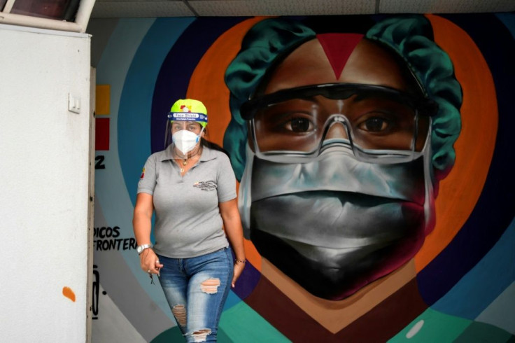 An employee passes before a mural on the wall of a Caracas hospital honoring the efforts of healthcare workers against Covid-19; Facebook has banned Venezuela's president Nicolas Maduro for a month for posting Covid misinformation