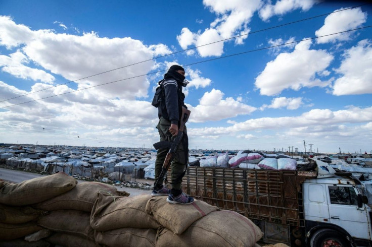 A member of the Kurdish internal security forces watches as a group of Syrian families is released in mid-March from the Kurdish-run Al-Hol camp