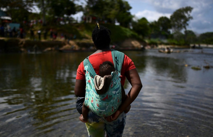 A migrant carrying a baby crosses the Chucunaque river after walking for five days in the Darien Gap