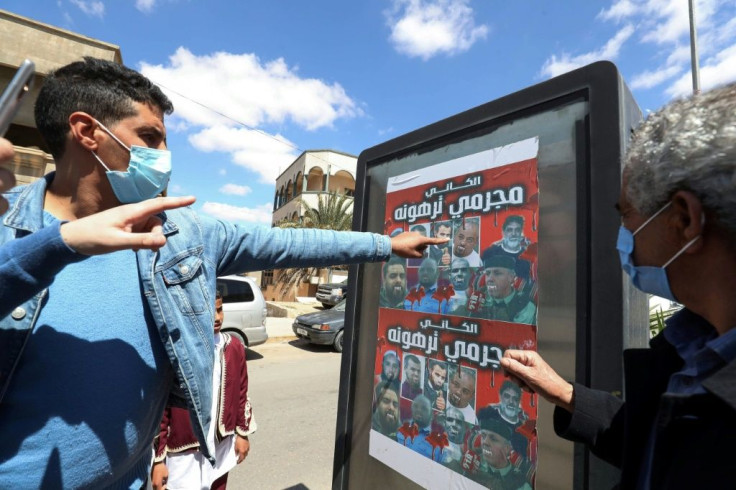 Libyans look at a poster depicting members of the family that commanded a militia that traumatised Tarhuna town