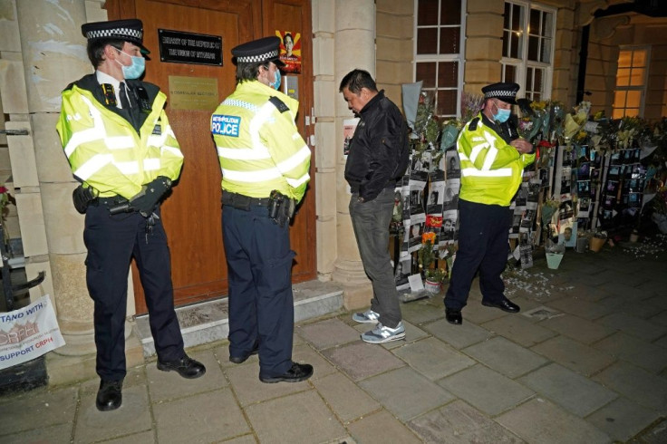 Myanmar's Ambassador to the United Kingdom, Kyaw Zwar Minn, stands with police officers locked outside the embassy in London