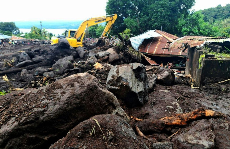 Rescuers use diggers and shovels to extract mud-covered corpses from the debris in Lamanele village, Indonesia