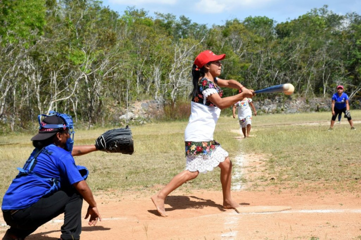 A player for the Little Devils of Hondzonot swings the bat during a softball game against the Piste Warriors in rural southeast Mexico