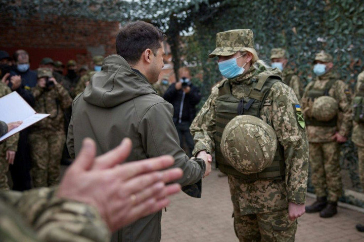 A masked President Zelensky greets an army officer in the eastern town of Zolote