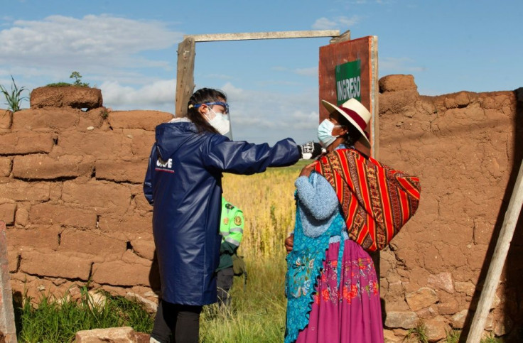 An election worker checks the temperature of a Quechua indigenous person arriving to vote at a polling station in the remote rural village of Capachica, in Puno, Peru, during general elections on April 11, 2021, amid the Covid-19 pandemic