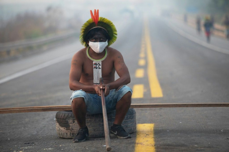 A member of the Kayapo tribe blocks a highway on the outskirts of Novo Progresso in Para State, Brazil, in August 2020 to protest illegal logging and mining in the rainforest and to seek action against Covid-19
