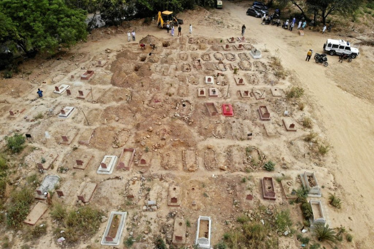 Around the graveyard, white body bags or coffins made out of cheap wood are carried around by people in blue or yellow protective suits and lowered into graves
